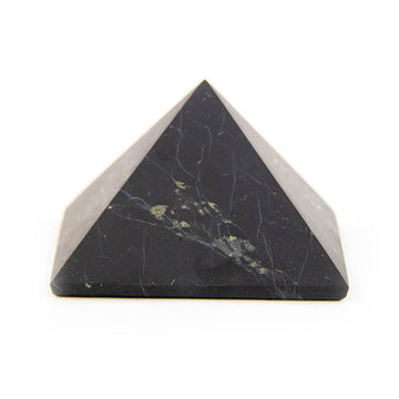 Shungite pyramid on white background, side view showing unpolished stone surface.